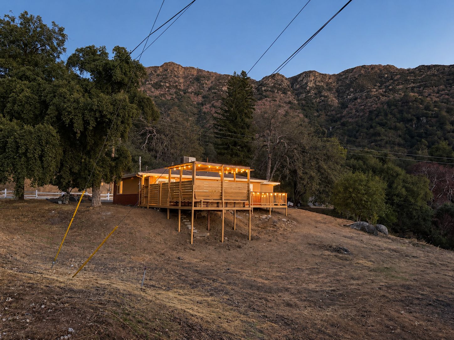 Une cabane en bois dotée d’une terrasse, entourée d’arbres et de collines.