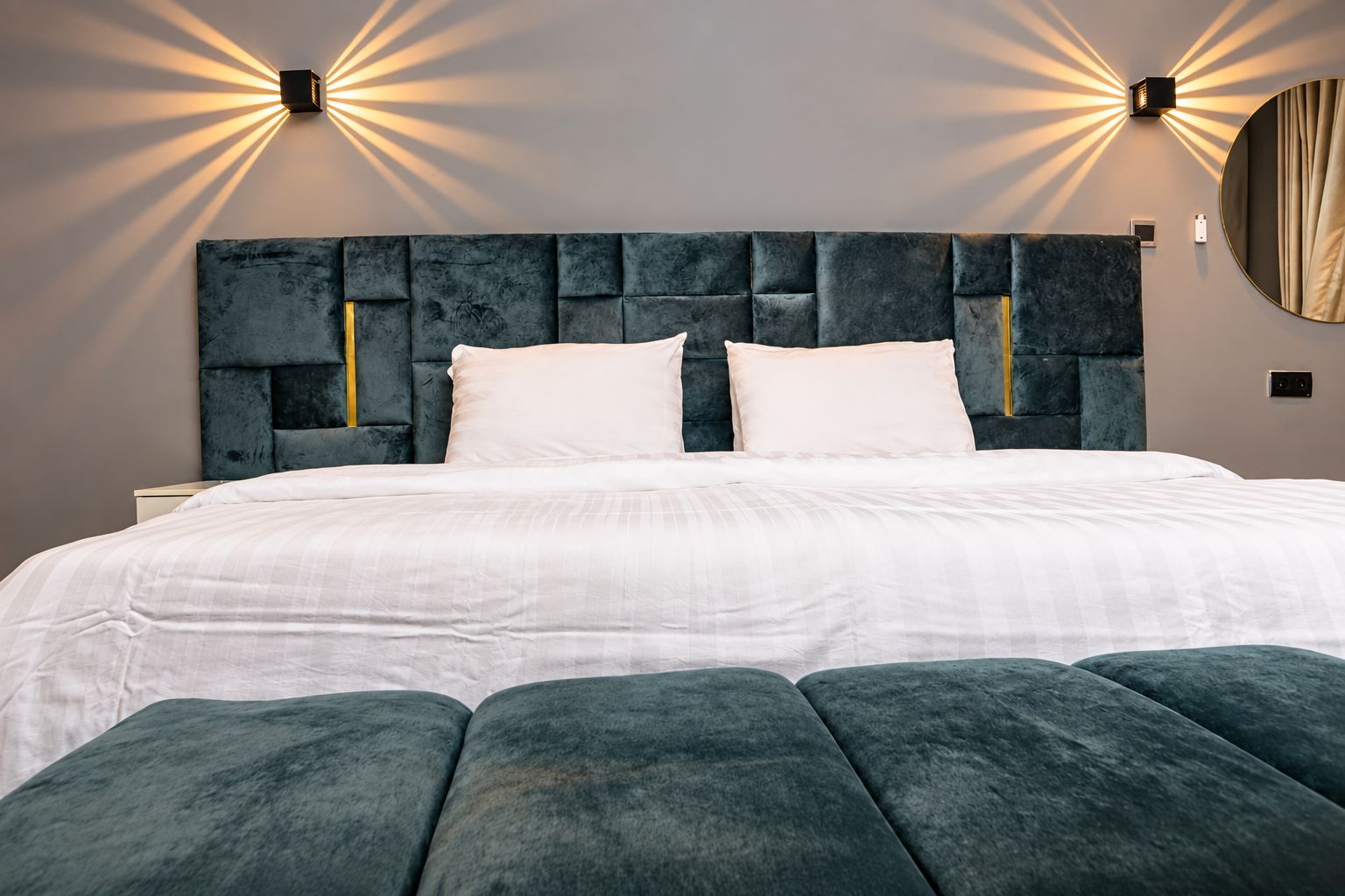 Ein modernes Schlafzimmer mit einem großen Bett, einer gesteppten Kopfteil und Wandleuchten.