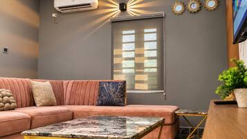 Ein Wohnzimmer mit einer Couch, einem Couchtisch und einem Fenster mit Jalousien.