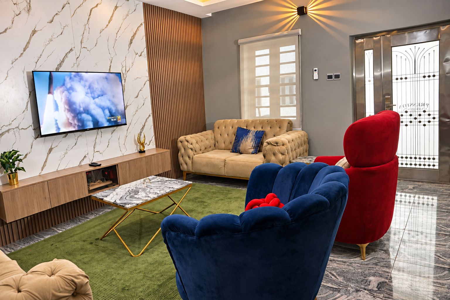 Una sala moderna con un sofá, un sillón rojo, un televisor y un adornado en la pared.