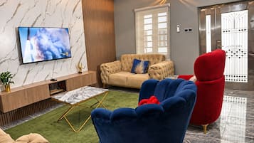 Una sala moderna con un sofá, un sillón rojo, un televisor y un adornado en la pared.