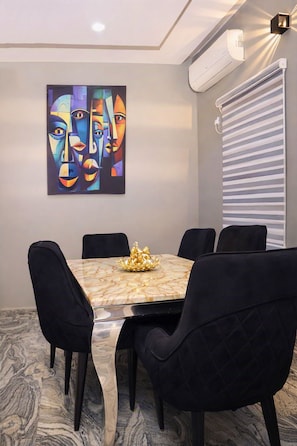 Una sala de conferencias con una mesa de mármol, sillas negras, un cuadro en la pared y un equipo de aire acondicionado.