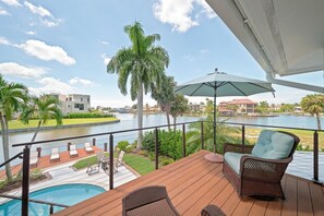 Uma varanda com piscina, móveis de exterior e vista para a água e edifícios.