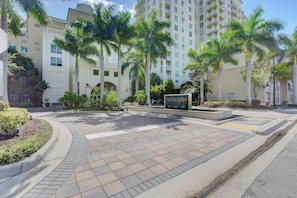 A hotel entrance with a paved walkway, palm trees, and a sign indicating the name and room numbers. - Casa Costa Coastal Retreat - Resort Pools & Beach (Boynton Beach)
