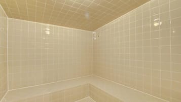 Un área de ducha con azulejos y un banco.