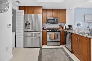 Une cuisine moderne dotée d’appareils électroménagers en acier inoxydable, d’armoires en bois et de plans de travail en granit.