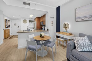 Una cocina moderna con una isla central, un comedor con una mesa redonda y una sala de estar con un sofá y un espejo decorativo.