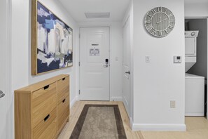 A hallway with a wooden cabinet, a painting, a clock, and a door with a 'No Smoking' sign. - Casa Costa Coastal Retreat - Resort Pools & Beach (Boynton Beach)