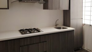 A modern kitchen with a gas stove, a stainless steel sink, and dark wooden cabinets. - Cozy Urban Apartment (Coxcatlán)