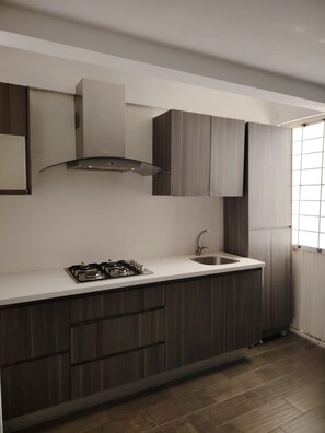 A modern kitchen with a gas stove, a stainless steel sink, and dark wooden cabinets.