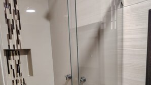 A modern bathroom with a glass-enclosed shower, a sink with a glass container, and a decorative wall panel. - Cozy Urban Apartment (Coxcatlán)
