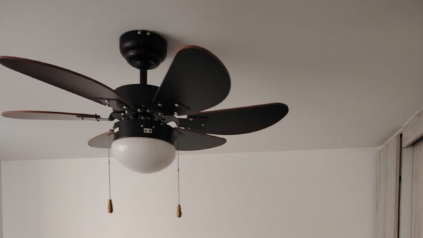 A bedroom with a bed, a ceiling fan, and a wardrobe. - Cozy Urban Apartment (Coxcatlán)