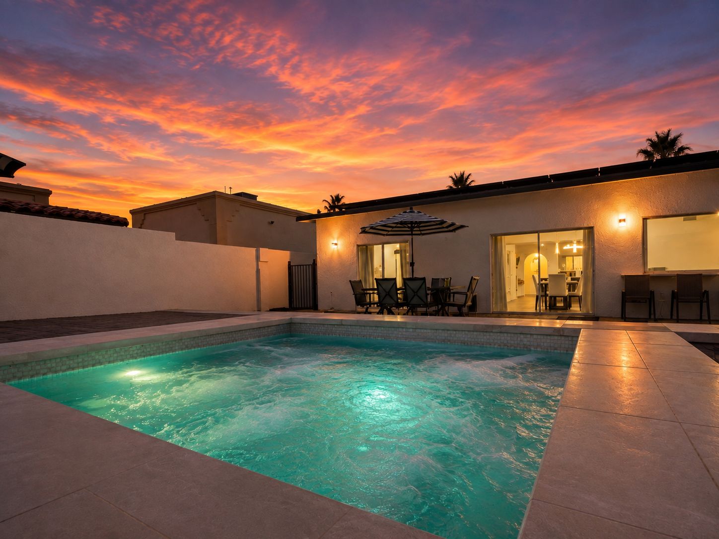 A swimming pool with a patio area, a covered seating area, and a building with a glass door.