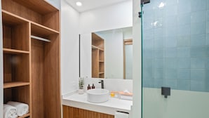 Een moderne badkamer met een houten wastafelmeubel, een witte wasbak en een grote spiegel.