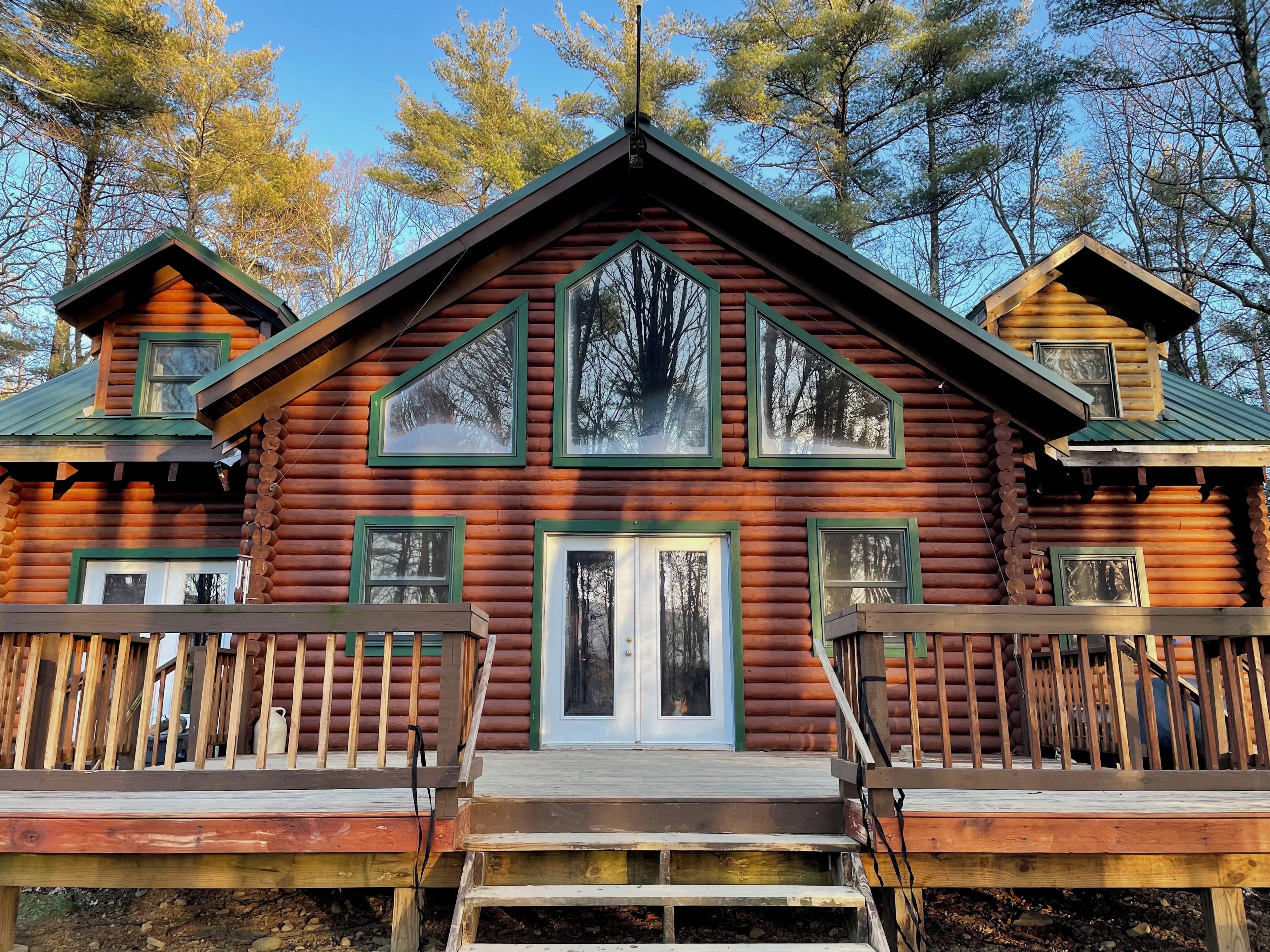 A log cabin with a central door, two side doors, and a small upper deck.