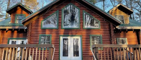 A log cabin with a central door, two side doors, and a small upper deck.