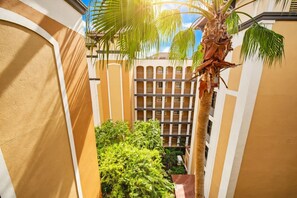 A multi-story building with balconies and a central courtyard with palm trees. - 2BR Disney Condo | FREE Resort Access & Parking (Orlando)