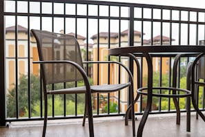 Un balcó amb taula i cadires, barana de metall i vista a edificis al fons.