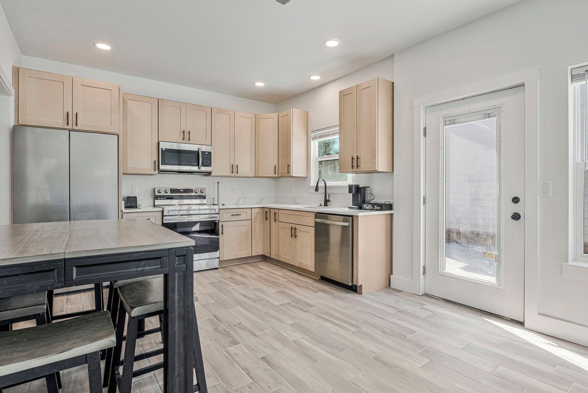 A modern kitchen with wooden cabinets, stainless steel appliances, and a dining area with a table and chairs.