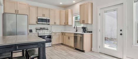 A modern kitchen with wooden cabinets, stainless steel appliances, and a dining area with a table and chairs.