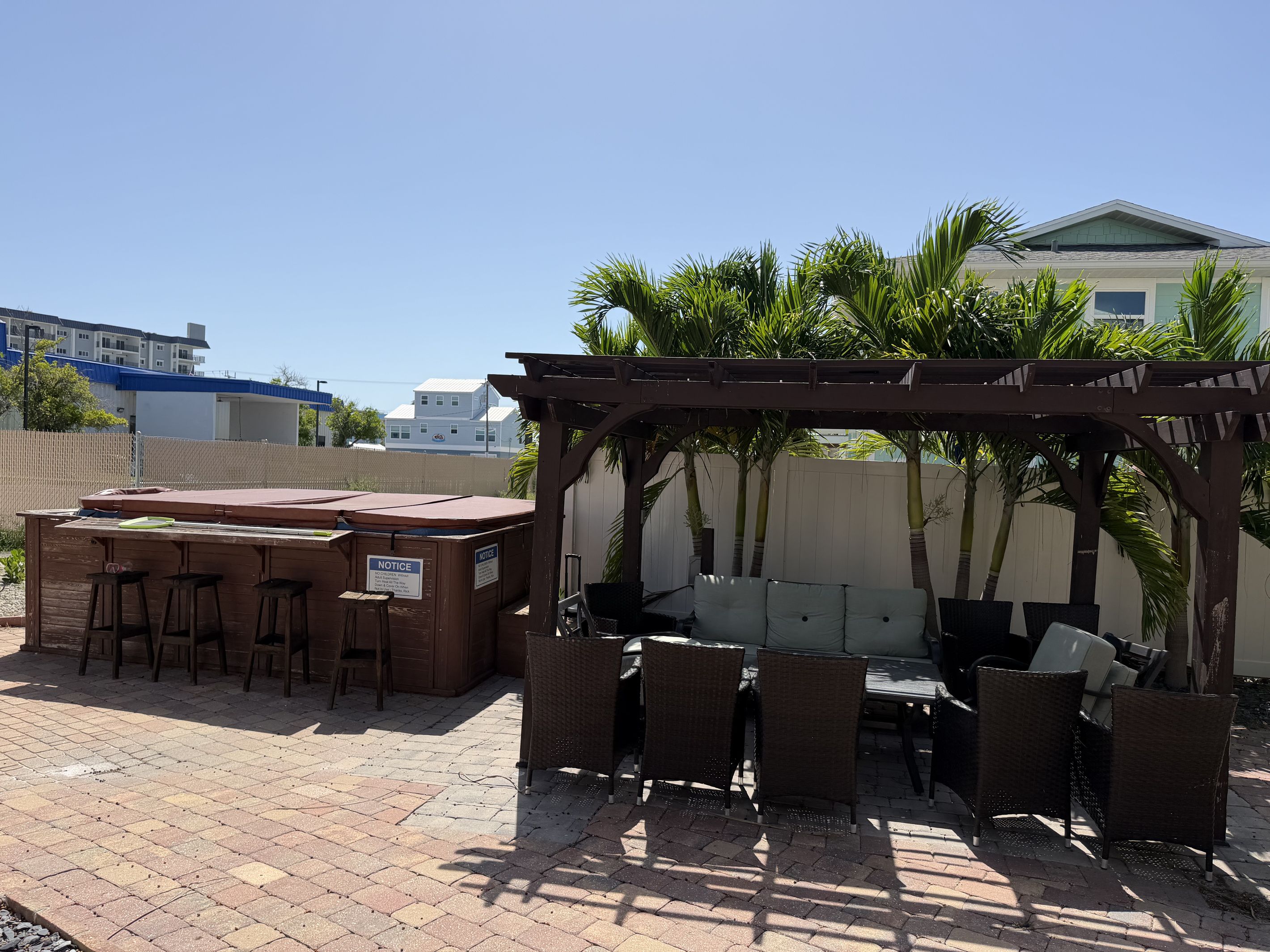 Een buitenpatio met een houten pergola, een barbecuehoek en rieten meubels.