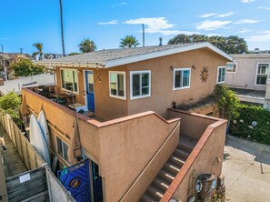 A two-story building with a balcony and a staircase leading to the upper floor. - 1 Block to Beach, Charming 3BR Newport Bungalow w/ Patios, Bikes & Gear (Newport Beach)