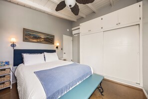 A bedroom with a bed, bedside lamps, a painting, a wardrobe, and a ceiling fan. - 1 Block to Beach, Charming 3BR Newport Bungalow w/ Patios, Bikes & Gear (Newport Beach)