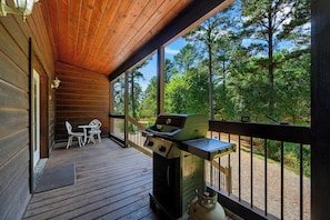 Eine Holzterrasse mit Grill und Gartenmöbeln.
