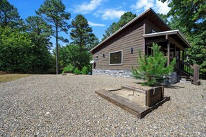 Eine Holzhütte mit Steinfundament, Holzverkleidung und Auffahrt mit Kies.