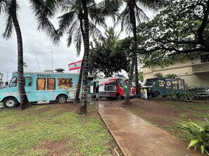 A food truck named BYBLOS EXPRESS parked in a grassy area with palm trees. - FREE PARKING!! 2 Bedroom Vacation Rental - Corner Unit with Great Views! (Honolulu)