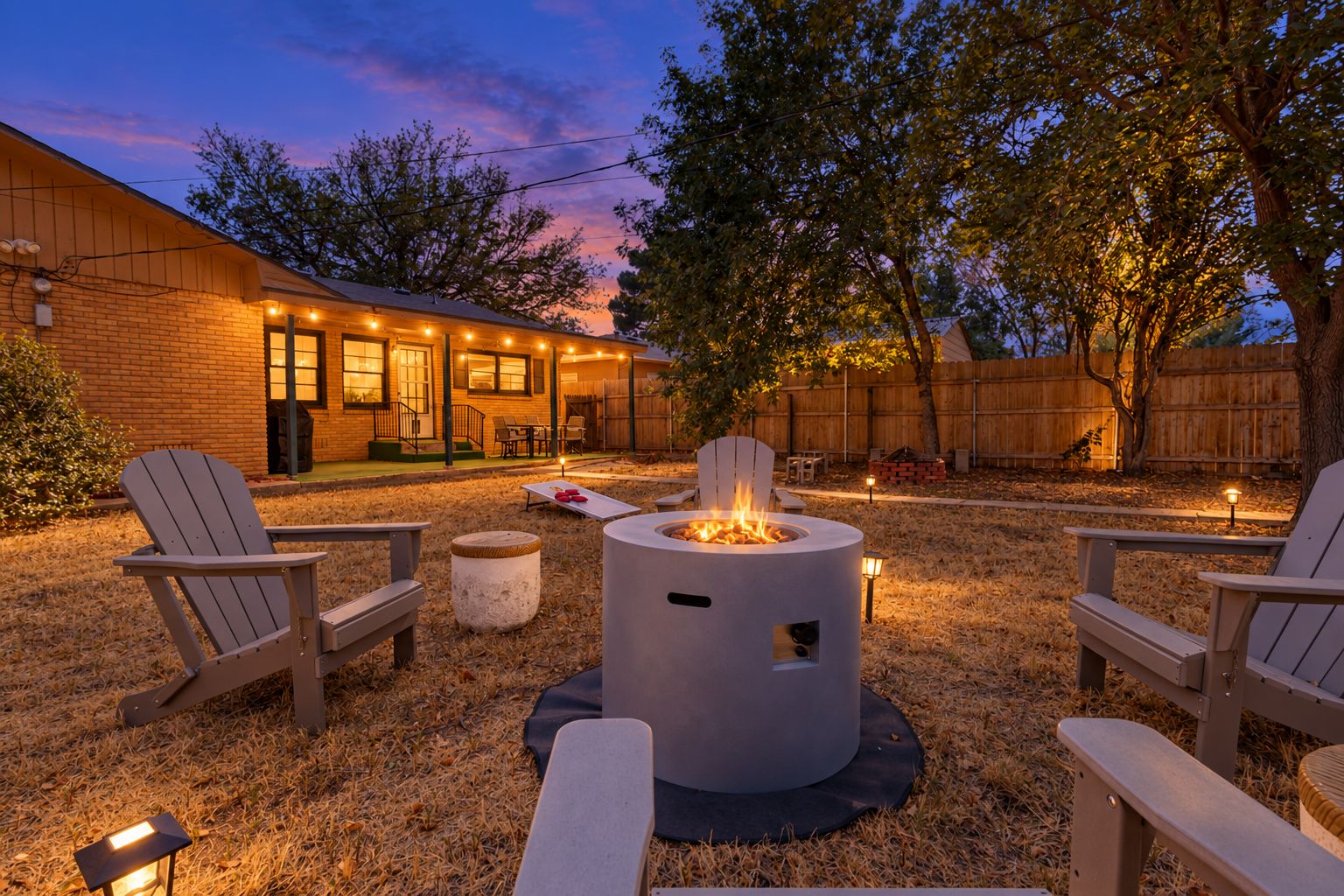 Un área de patio al aire libre con sillas Adirondack, un brasero y un edificio de ladrillo al fondo.