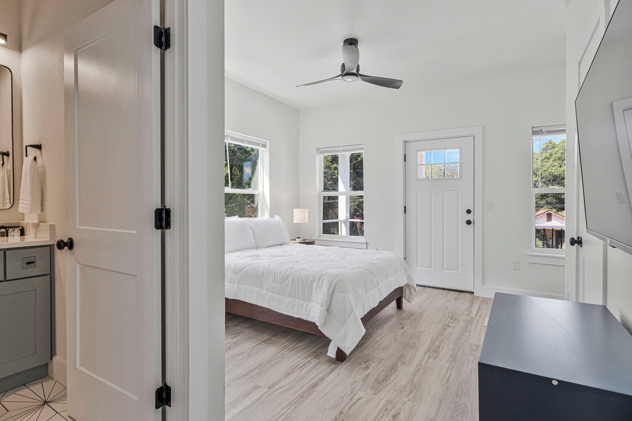 Une chambre à coucher avec un lit, un ventilateur de plafond et une porte avec une fenêtre.