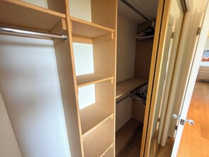 Ein begehbarer Kleiderschrank mit offenen Regalen, einer Kleiderstange und einer Tür mit Griff.