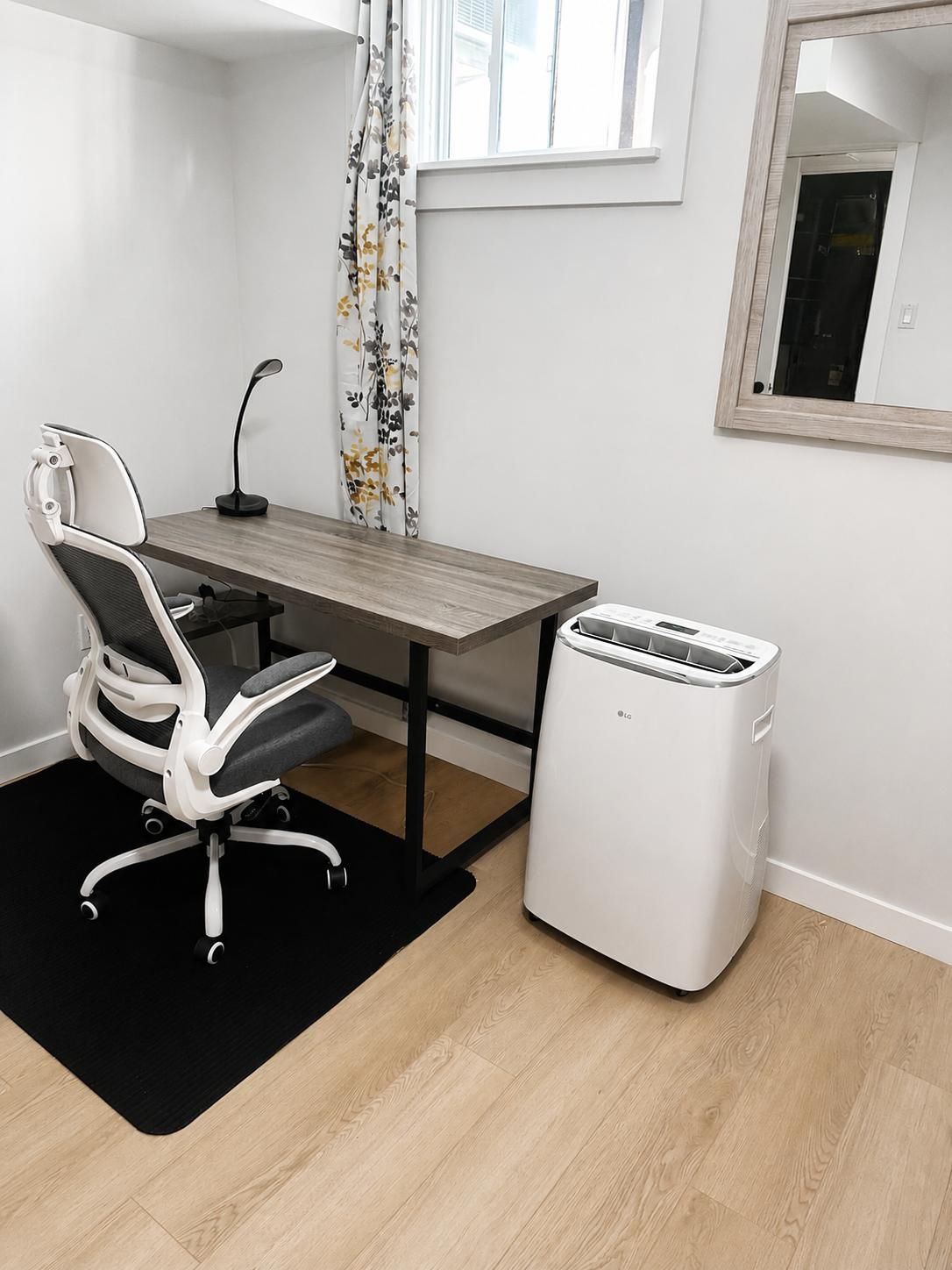 A modern office space with a desk, chair, and a white LG air purifier.