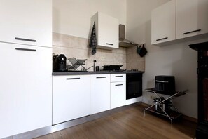 A modern kitchen with white cabinets, a coffee machine, and a kettle on the countertop.