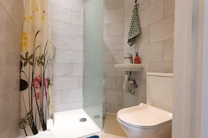 A bathroom with a shower, toilet, sink, and a glass-enclosed shower stall. - Chic and elegant 3-bedroom apartment (Molenbeek-Saint-Jean)