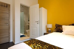 A bedroom with a bed, a wardrobe, and a bathroom visible through an open door. - Chic and elegant 3-bedroom apartment (Molenbeek-Saint-Jean)