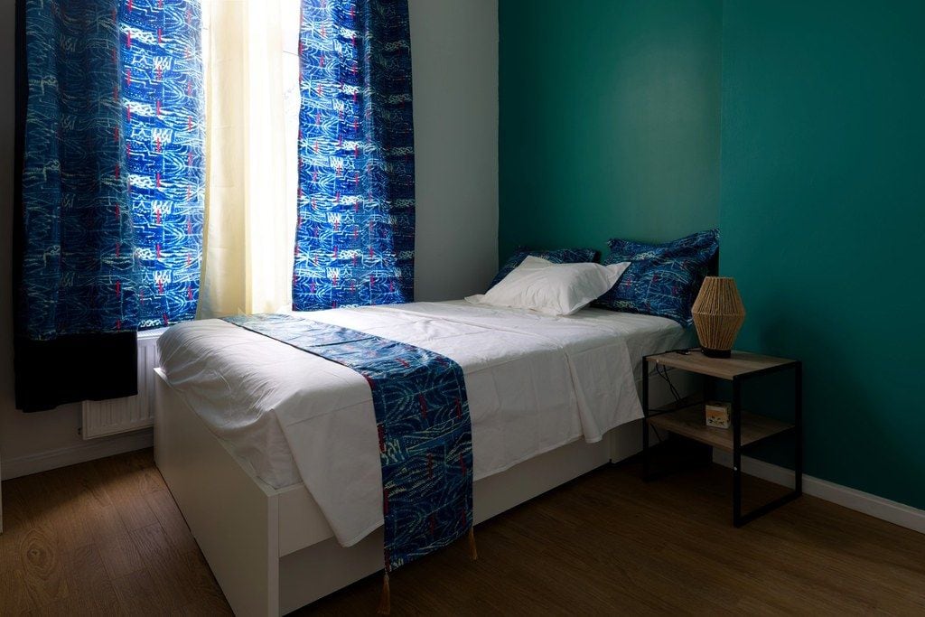Une chambre à coucher avec un lit, une table de chevet et des rideaux.