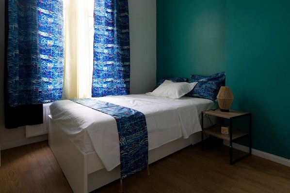 A bedroom with a bed, a bedside table, and curtains.