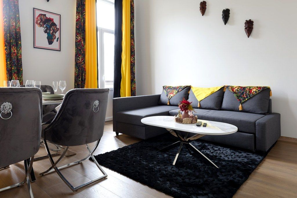 Un salon avec un canapé gris, une table basse ronde et deux fauteuils.