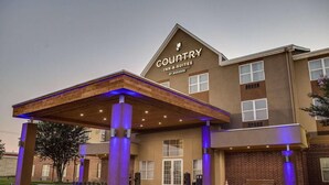 Ein Country Inn & Suites Gebäude mit überdachter Eingangspartei, großen Fenstern und einer Ziegel-Fassade.