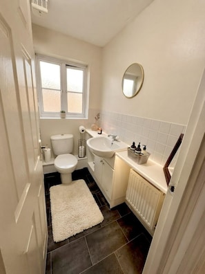 Un baño pequeño con inodoro, lavabo y espejo en la pared.