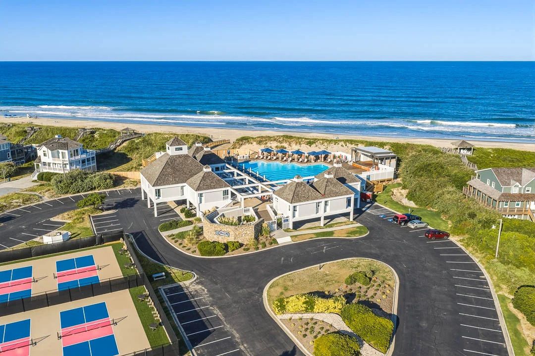 A coastal hotel with a swimming pool, parking, and beachfront views.