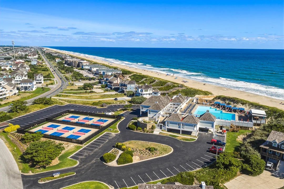 A coastal residential area with a swimming pool, beach access, and a parking lot.