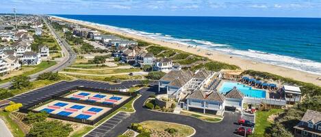 A coastal residential area with a swimming pool, beach access, and a parking lot.