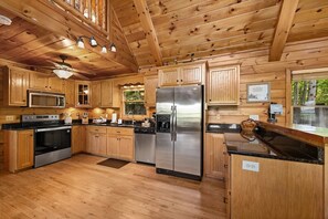 A wooden cabin kitchen with a stainless steel refrigerator, wooden cabinets, and a black countertop. - Always on My Mind - Mountain View | Pet Friendly | Hot Tub | Firepit (Mineral Bluff)