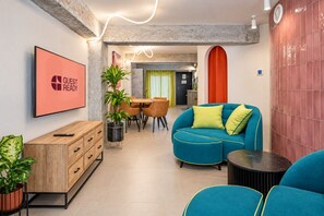A modern living room with a blue sofa, a wooden cabinet, and a dining area with a table and chairs. - Guestready - Malaga Art and Comfort Apartments (Málaga)