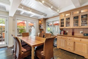 A spacious kitchen with a wooden dining table and chairs, built-in cabinets, and a view through large windows. - Kimberly Luxury Cabin - Hot Tub, Walk to Town (Tahoe City)
