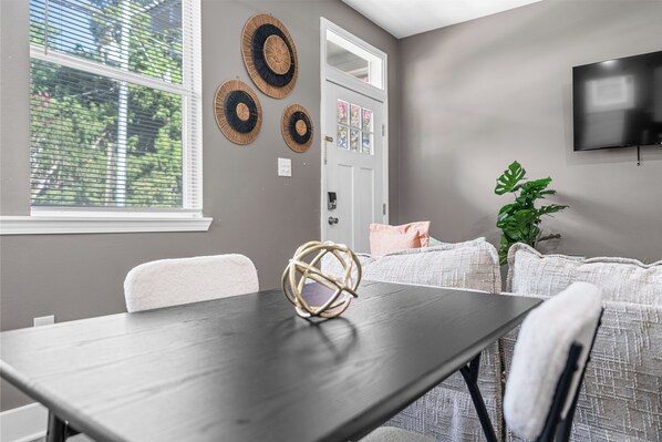 A dining area with a dark wooden table, white chairs, and a decorative sphere.