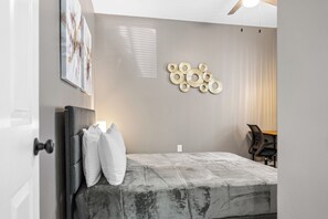 Ein Schlafzimmer mit einem Bett, einem Schreibtisch und einer Wandlampe.